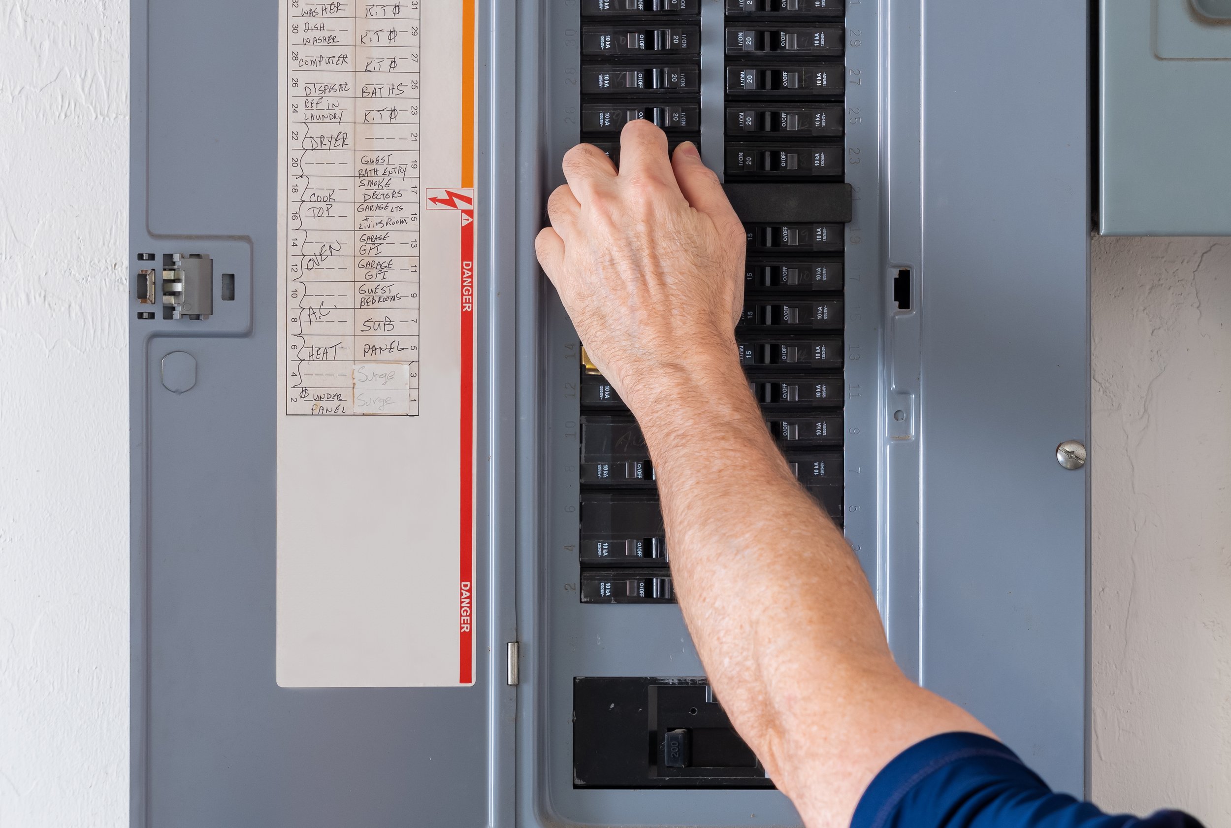 A residential breaker panel with the cover removed, showing rows of labelled circuit breakers and a printed circuit directory.