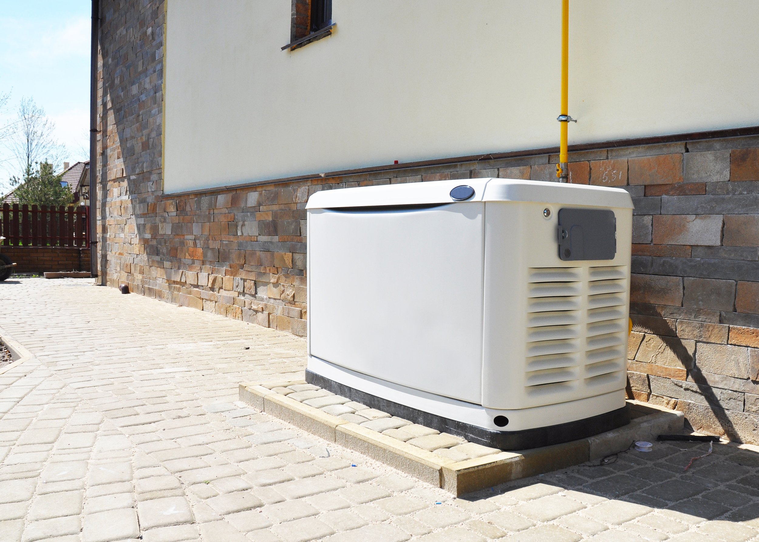 An outdoor air conditioning or heat pump unit installed next to a stone and stucco building.